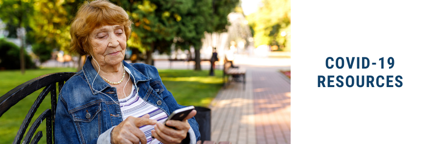 Older adult woman using smart phone, wearing headphones, on a park bench